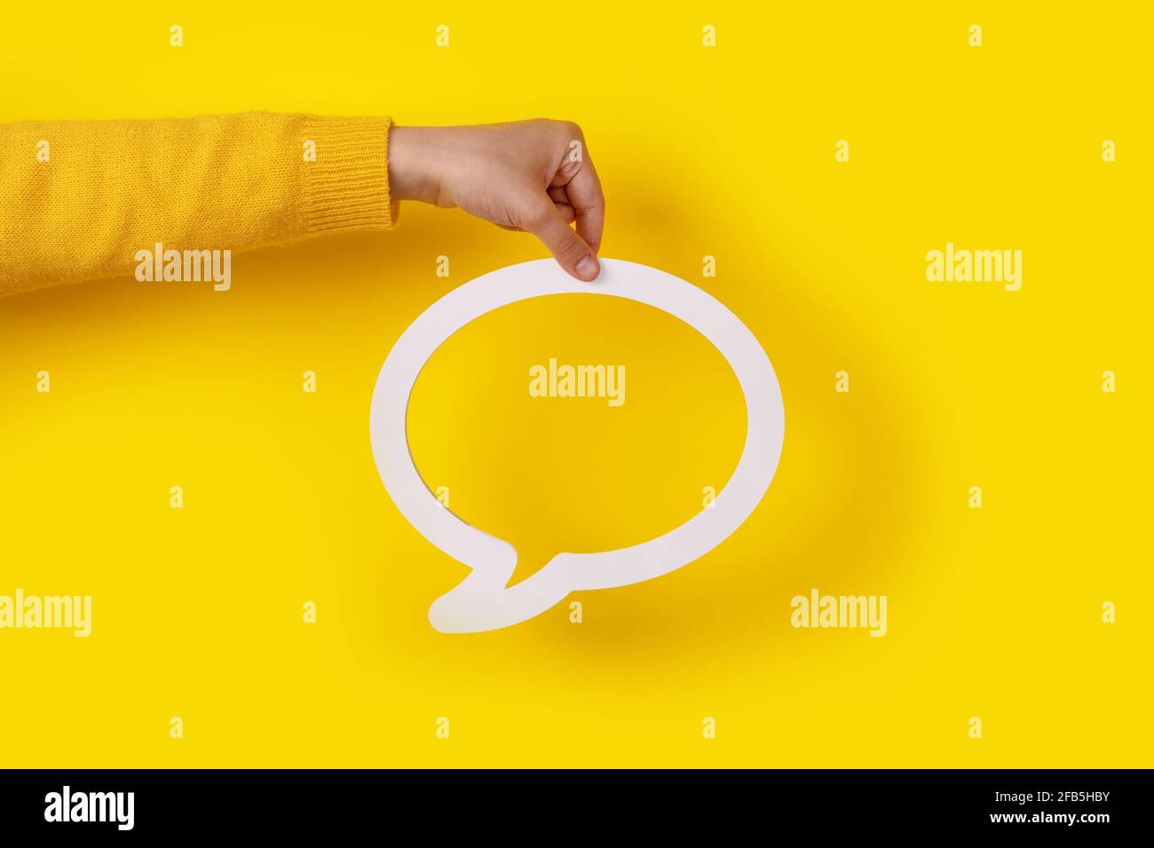Bolla di dialogo in mano su sfondo giallo Foto Stock