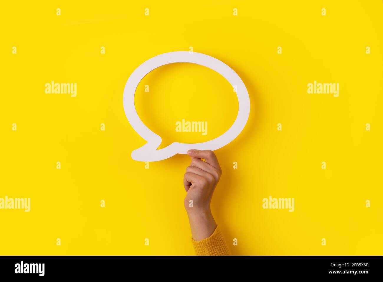 tenendo la mano la bolla di dialogo su sfondo giallo Foto Stock