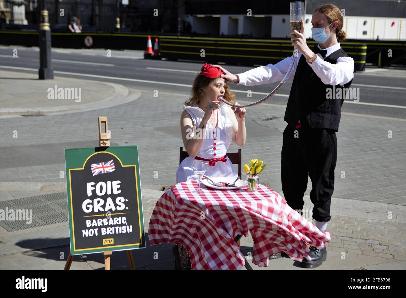 Londra, Regno Unito. 23 Apr 2021. Il giorno di San Giorgio, 23 aprile, un sostenitore del PETA (People for the Ethical Treatment of Animals) in un abito rosso e bianco in stile bandiera inglese si siede a un tavolo da pranzo - sotto il quale un cartello recita "Foie Gras: Barbaro, non britannico" - e si faccia "forzare" la sua cena attraverso un tubo. Lo stesso modo in cui i produttori di foie gras pompano grano negli stomachi di oche terrorizzate e anatre per allargare i loro fegati, un processo che è così non-britannico è illegale nel Regno Unito. (Foto di Pietro Recchia/SOPA Images/Sipa USA) Credit: Sipa USA/Alamy Live News Foto Stock