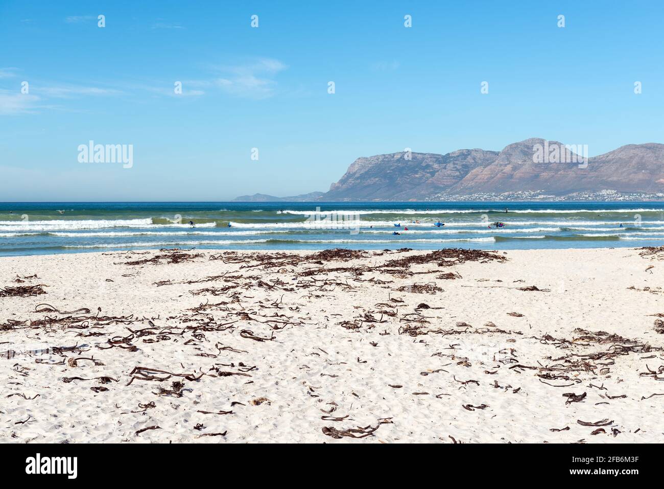 Persone sudafricane surfing nelle onde vicino Città del Capo con Table Mountain sfondo, Muizenberg Beach, Sud Africa. Foto Stock