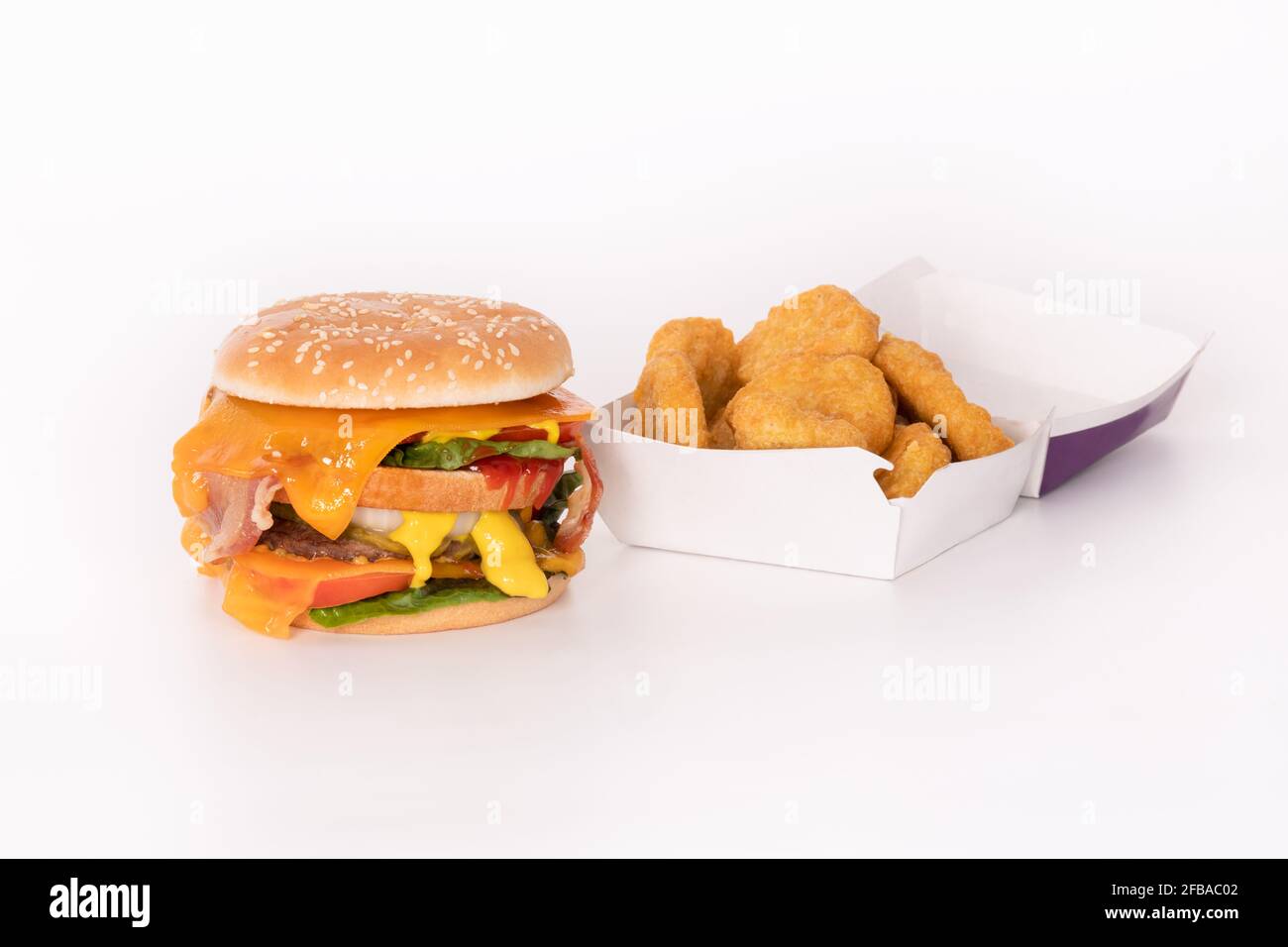 Hamburger grande accanto a una scatola di pepite di pollo Foto Stock