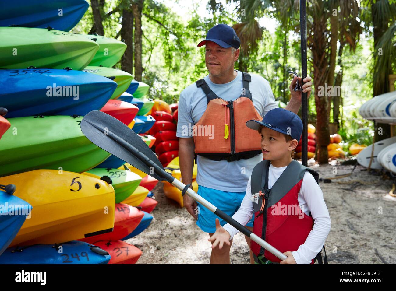 Figlio con ruggito che guarda la canoa mentre si trova in piedi da padre Foto Stock