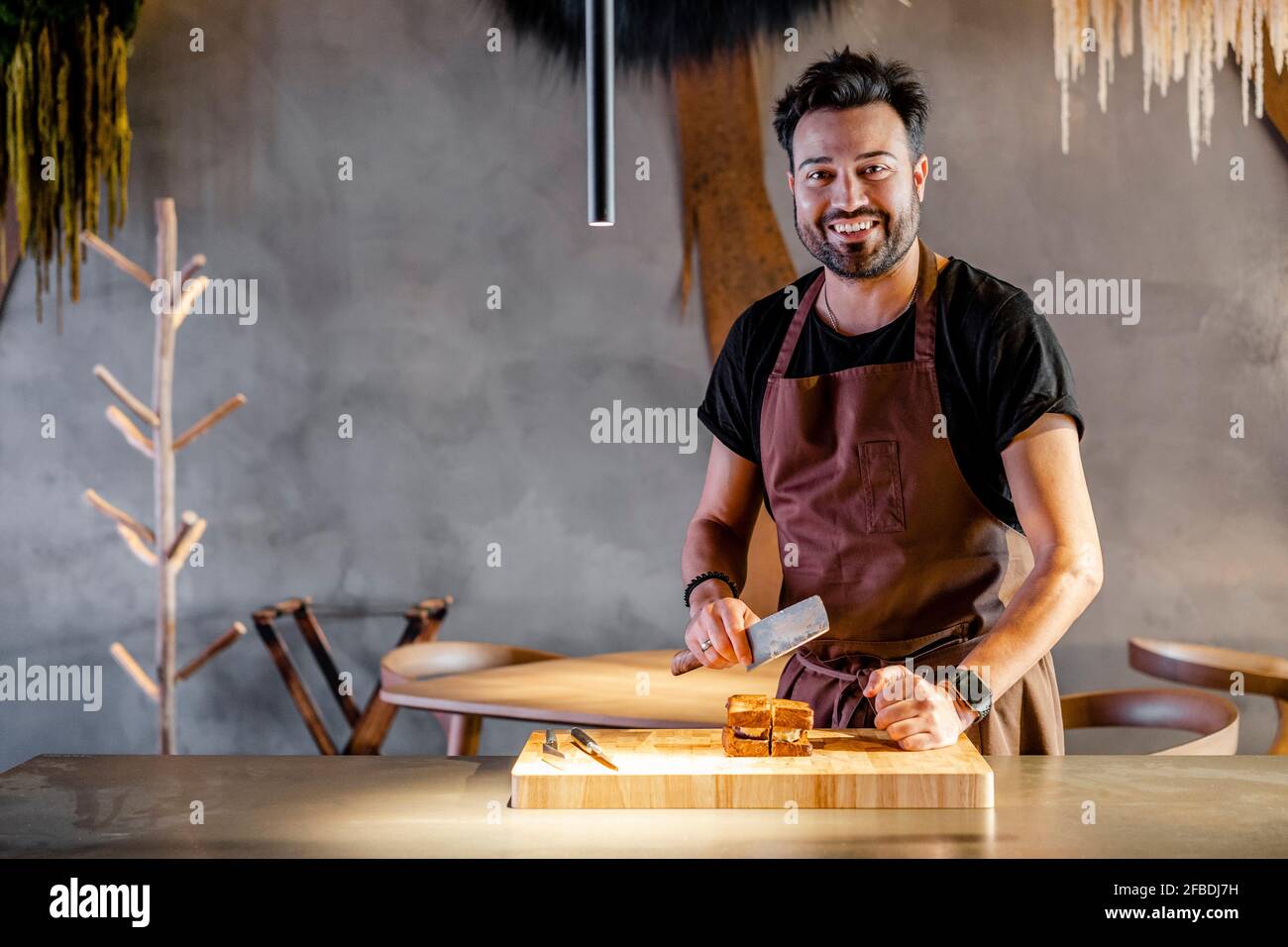 Chef sorridente con carne sfaldante in piedi da cibo in commercio cucina Foto Stock