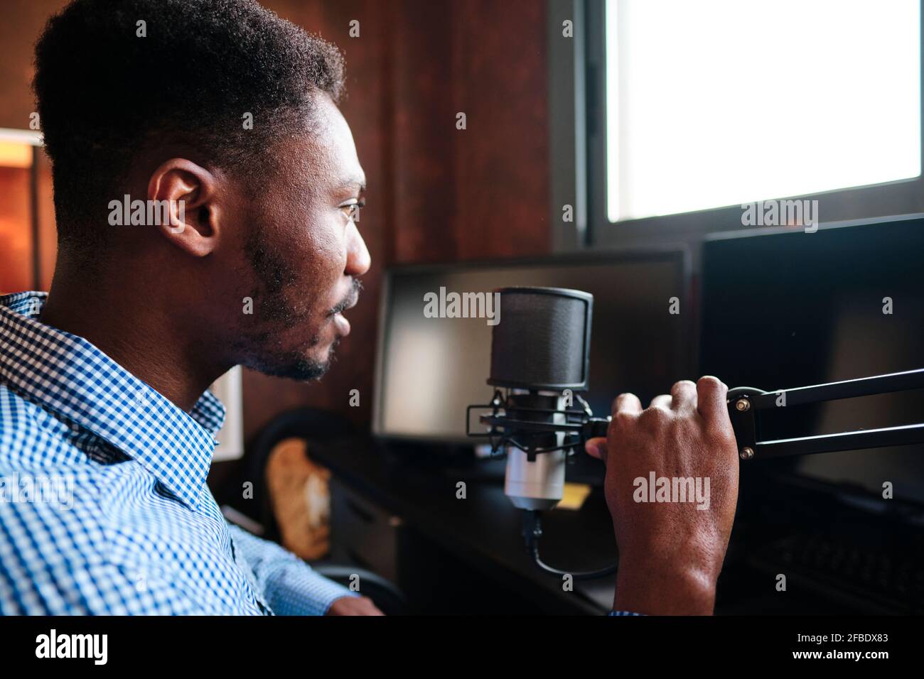 L'influencer medio-adulto tiene il microfono durante il podcast a casa Foto Stock