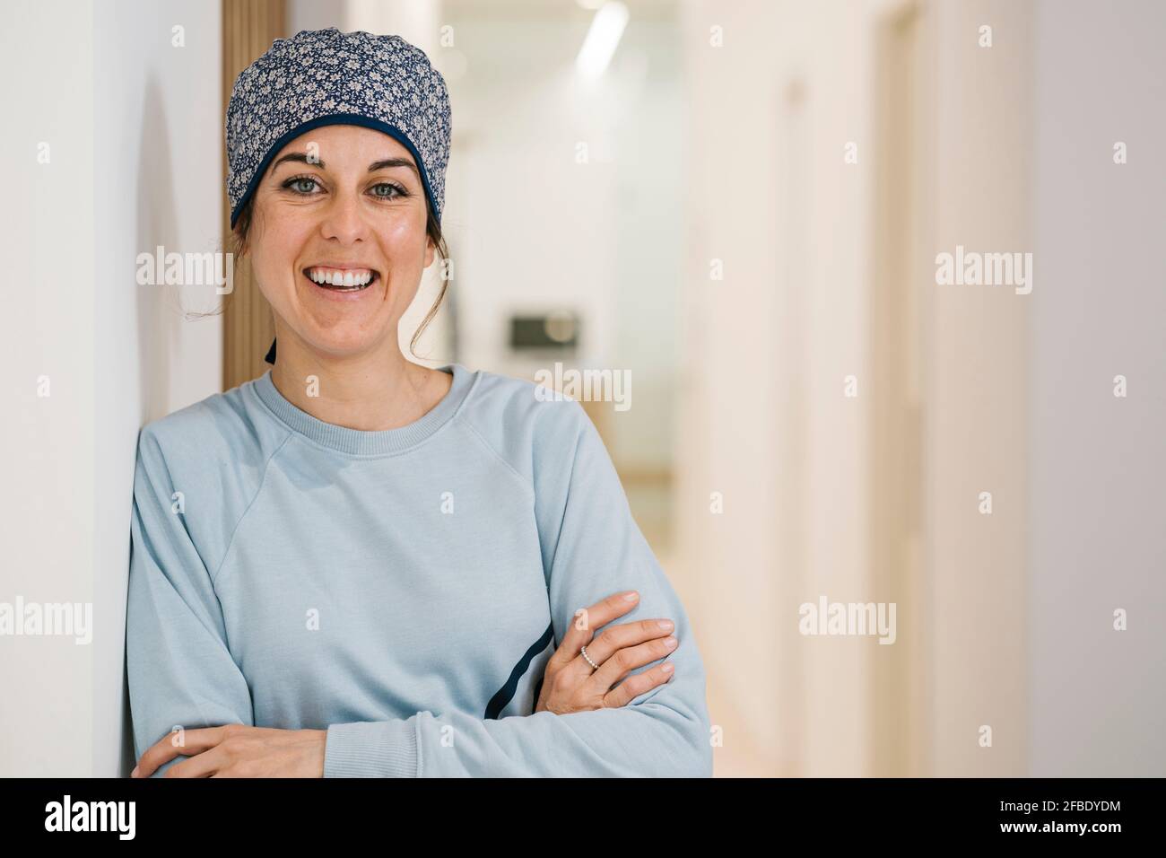 Felice ortodontista femmina sorridente mentre si sta in piedi con le braccia incrociate a. corridoio della clinica Foto Stock