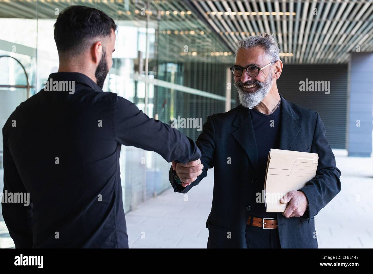 Sorridente imprenditori maschi che fanno stretta di mano all'ingresso Foto Stock