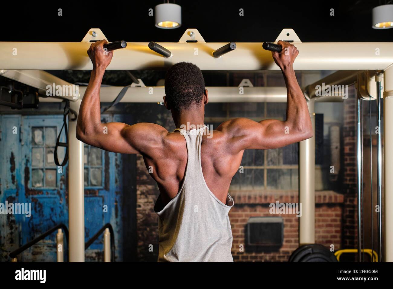 Atleta maschile che fa chin-up in palestra bar Foto Stock