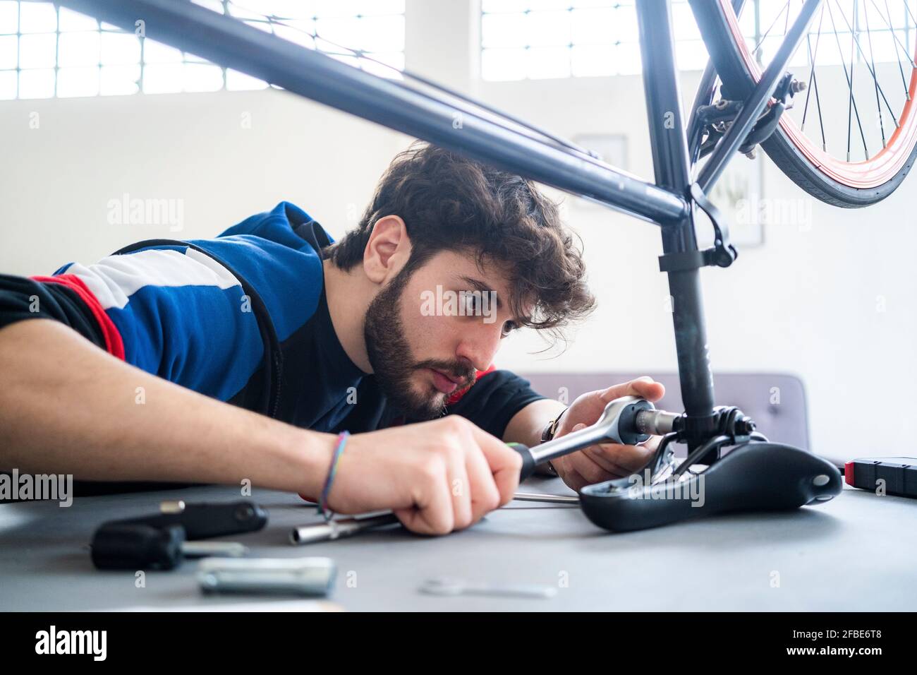 Uomo che fissa il sedile per bicicletta con chiave a casa Foto Stock