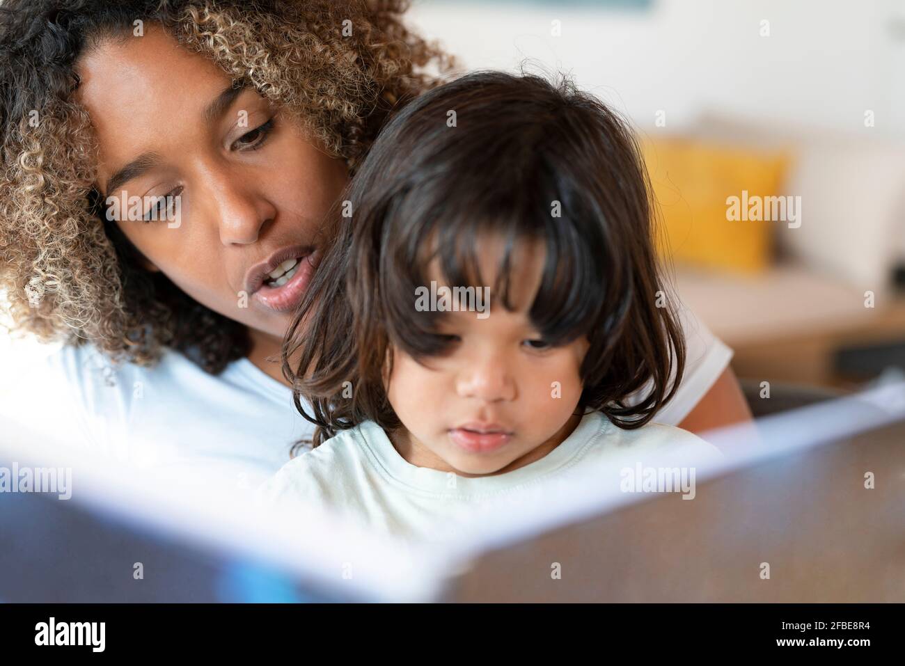 Madre lettura libro a sua figlia a casa Foto Stock