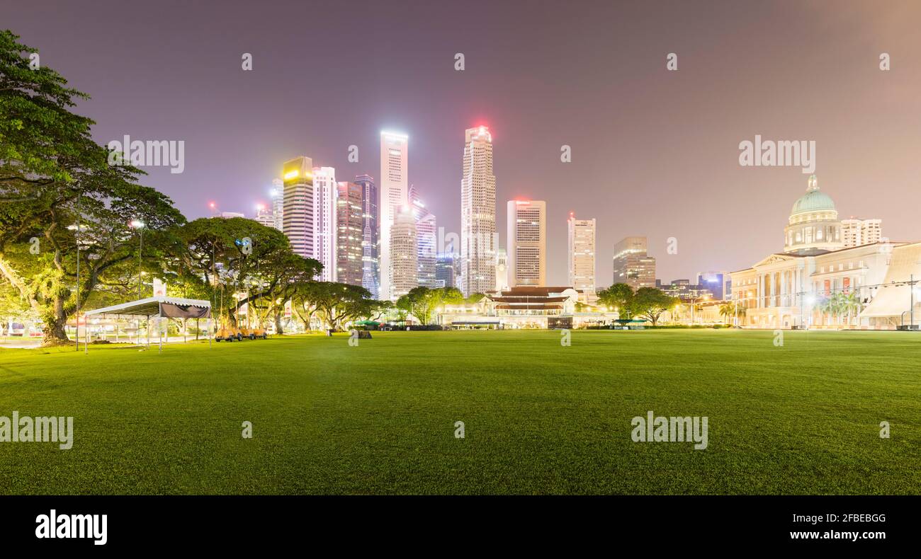 Singapore, Padang Field di notte con skyline della città illuminato sullo sfondo Foto Stock