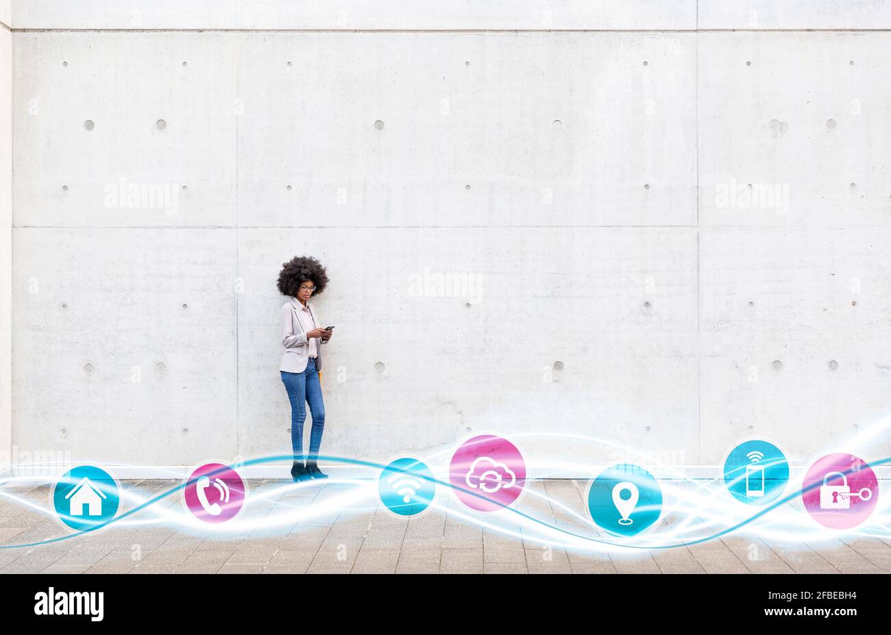 Donna imprenditore che utilizza il telefono cellulare mentre si è in piedi con le icone andamento delle onde incandescenti a parete Foto Stock