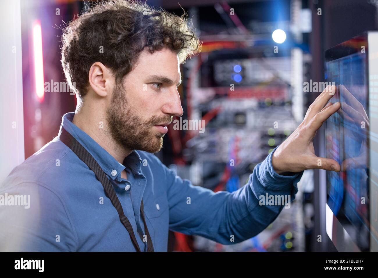 Tecnico IT maschile che guarda lo schermo del computer nel data center Foto Stock
