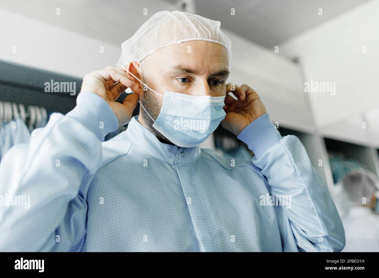 Ritratto di scienziato maschile che mette sulla maschera protettiva del viso Foto Stock