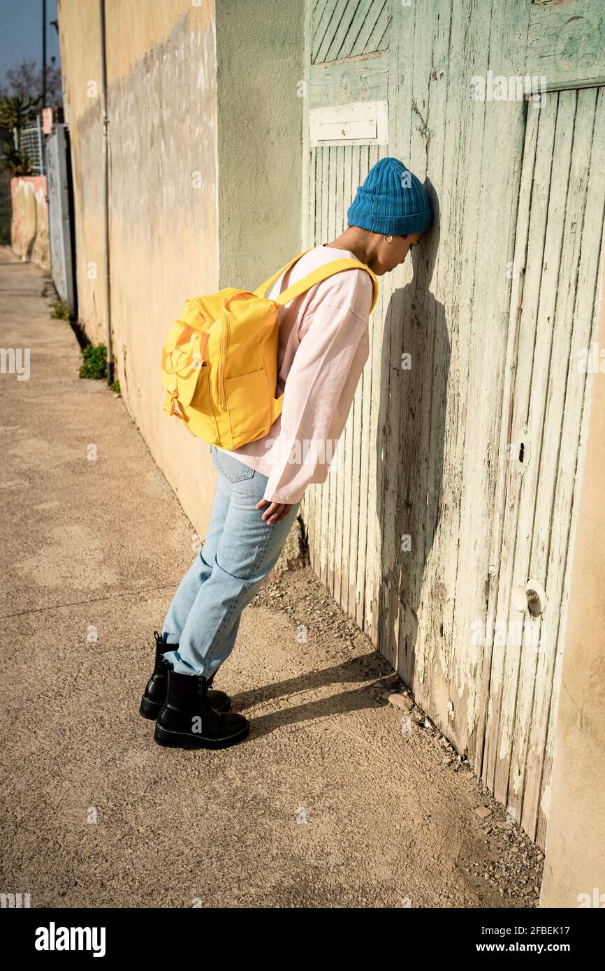 Donna in maglia cappello appoggiata sulla porta durante il giorno di sole Foto Stock