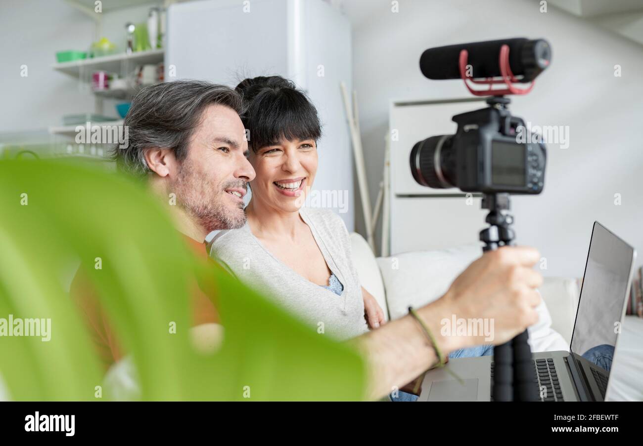 Felice coppia vlogging attraverso fotocamera digitale a casa Foto Stock