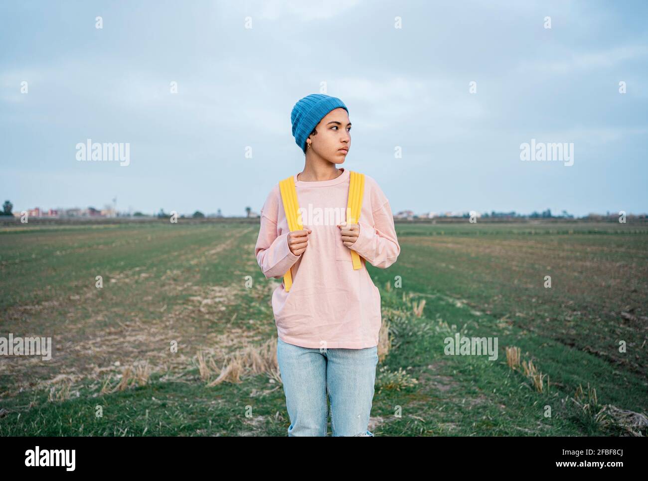 Donna con zaino che guarda via mentre si sta in piedi su campo verde Foto Stock