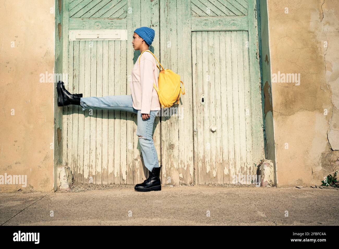 Donna con zaino in piedi su una gamba da porta di legno durante il giorno di sole Foto Stock