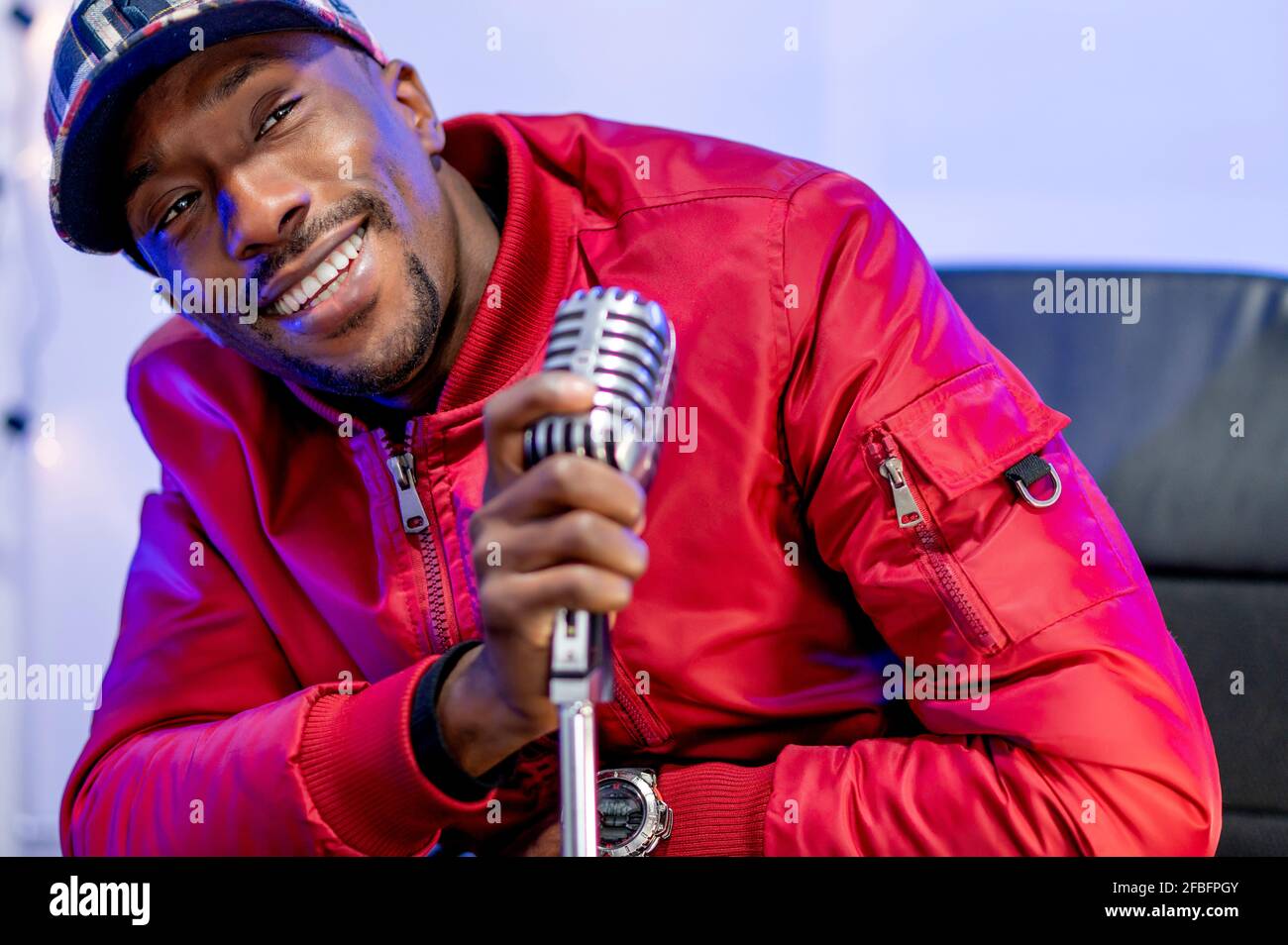 Sorridente influencer maschio che tiene il microfono in studio Foto Stock