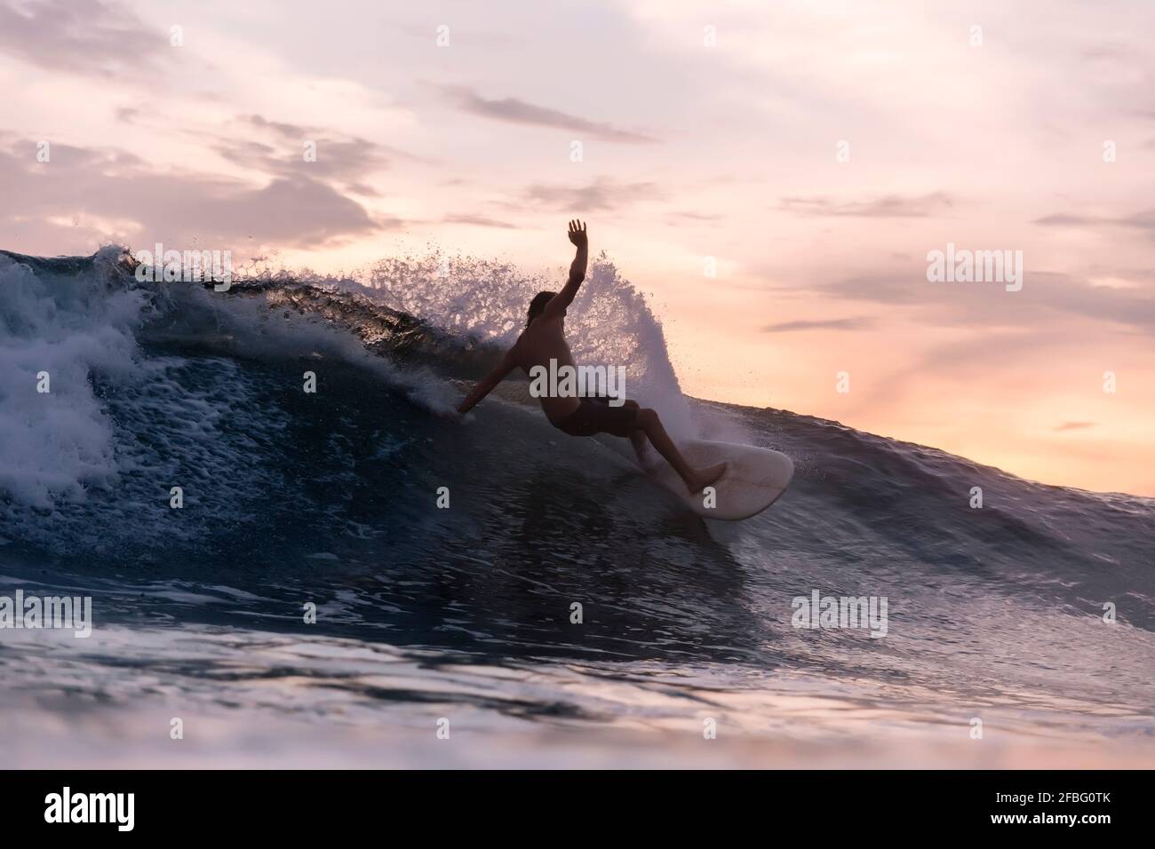 Surf turistico sulle onde in mare durante il tramonto Foto Stock