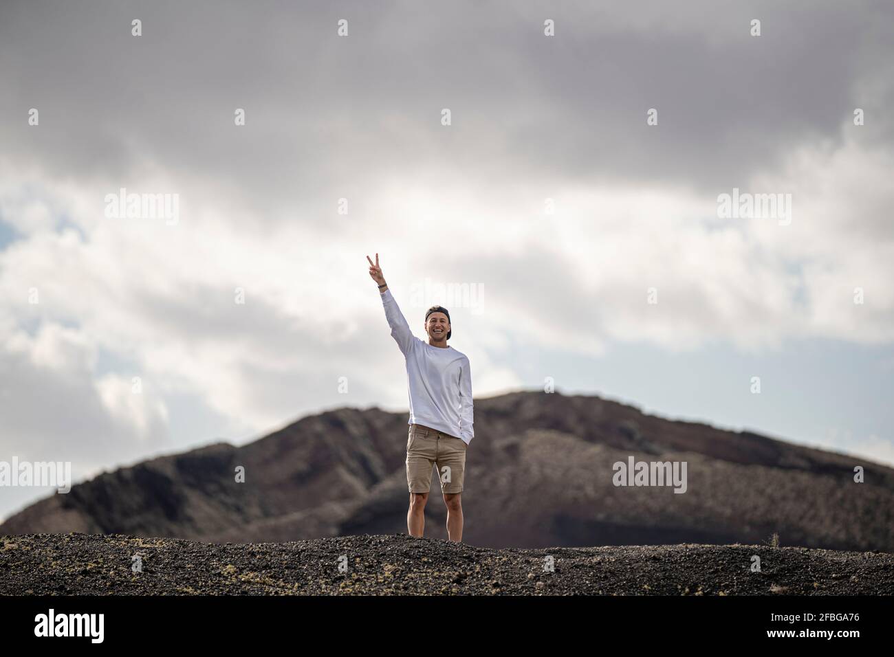 Caucasica maschile turista pace gesturing mentre si trova a el cuervo vulcano Foto Stock