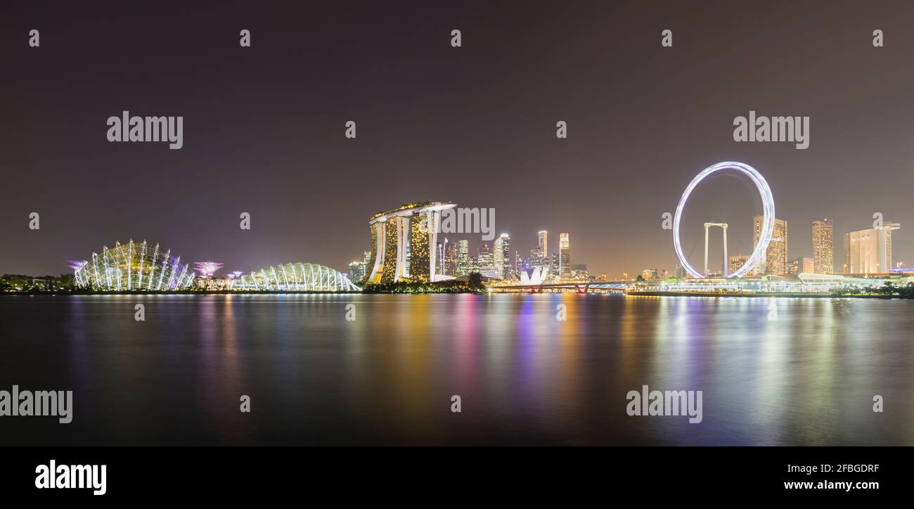 Singapore, lunga esposizione di Marina Bay di notte con l'hotel Marina Bay Sands e Singapore Flyer sullo sfondo Foto Stock