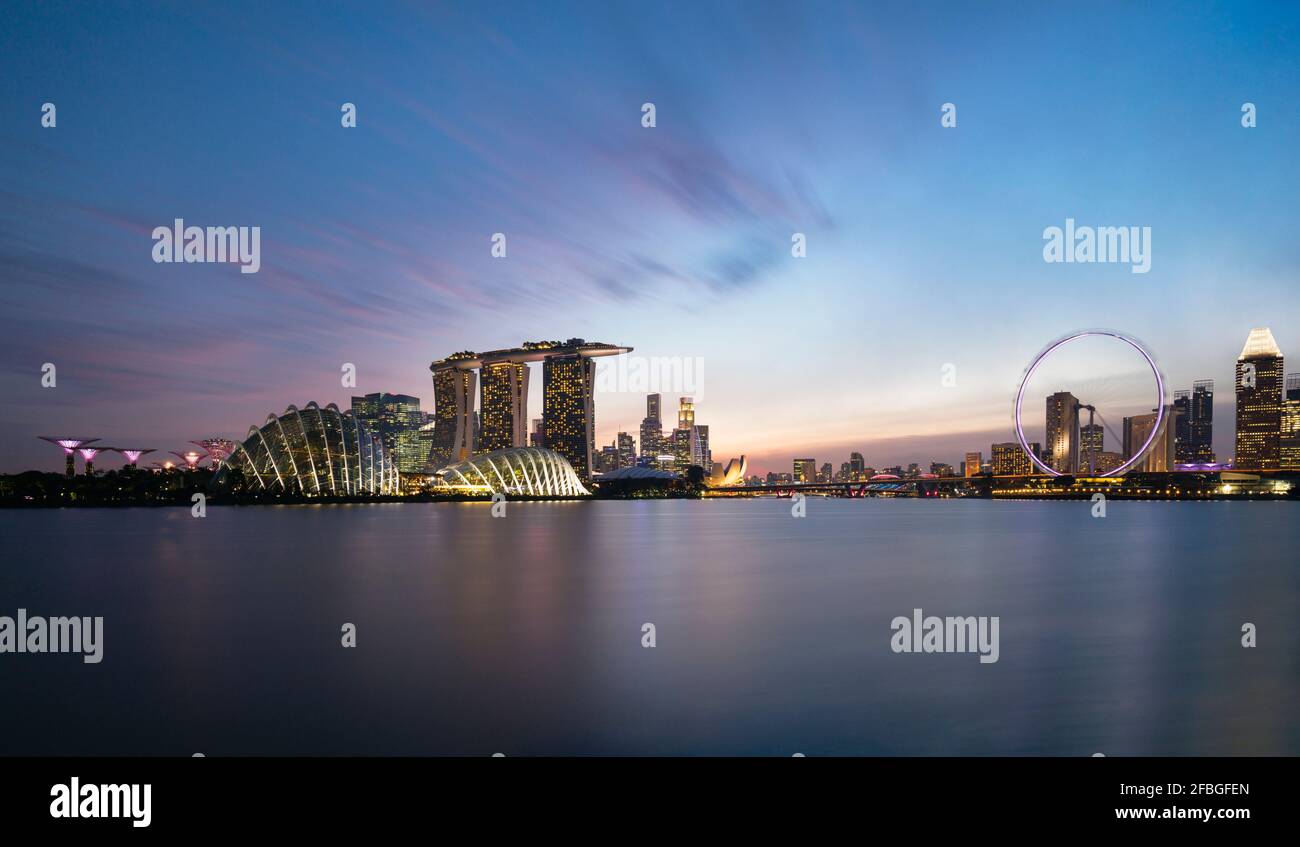 Singapore, lunga esposizione di Marina Bay al tramonto con l'hotel Marina Bay Sands e Singapore Flyer sullo sfondo Foto Stock