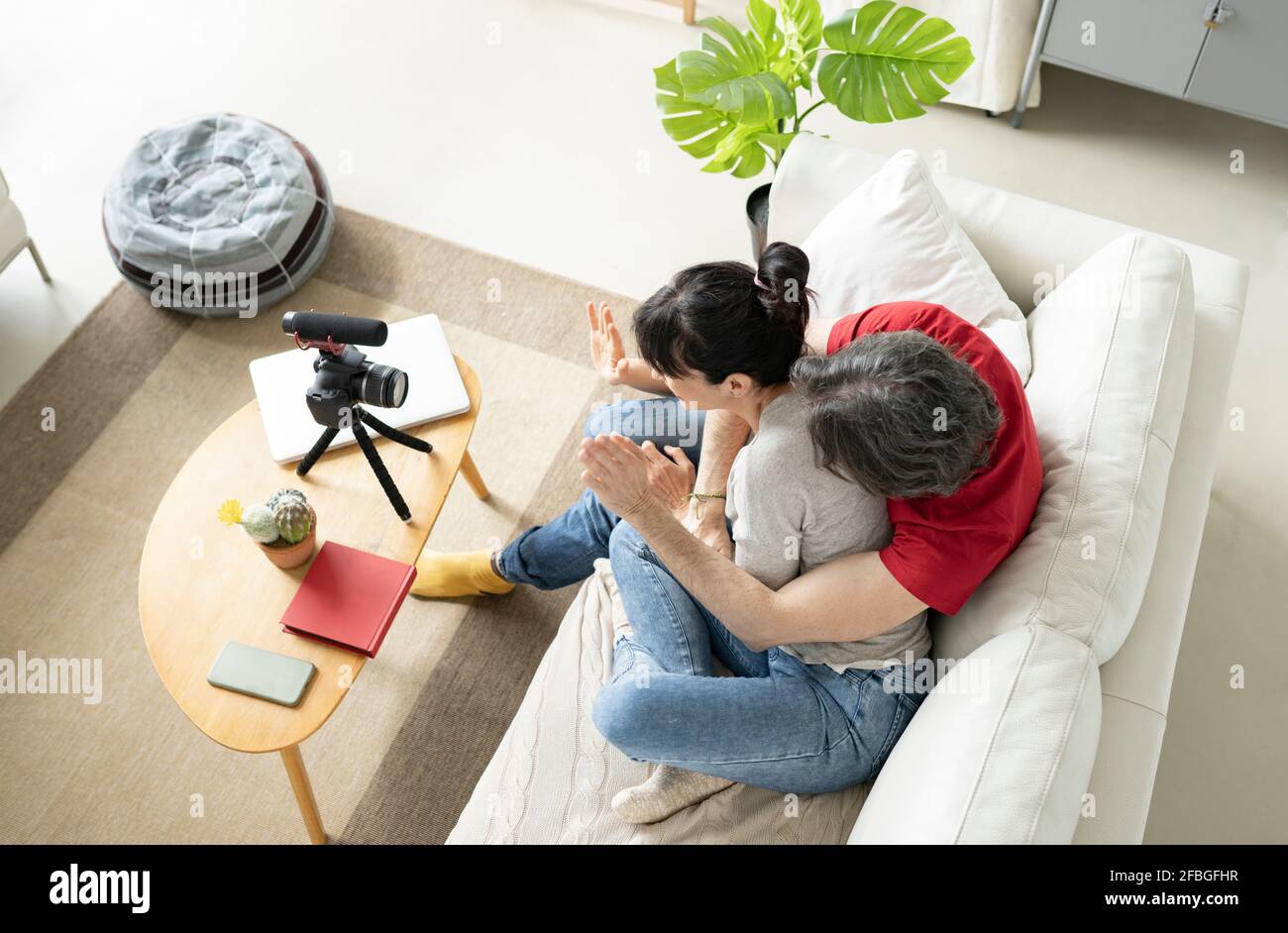 Una coppia giocosa che vlogging attraverso la fotocamera digitale a casa Foto Stock