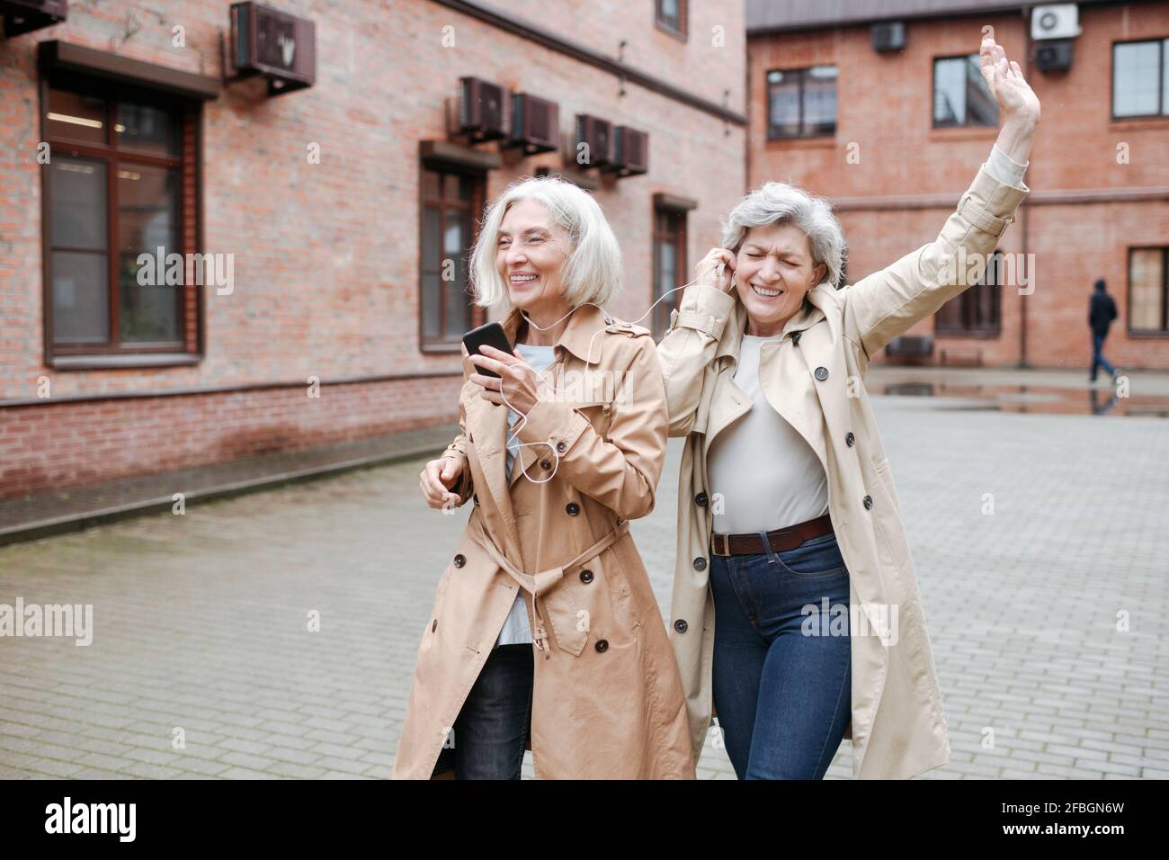 Felici le amiche che condividono le cuffie mentre ascoltano musica e ballano Foto Stock