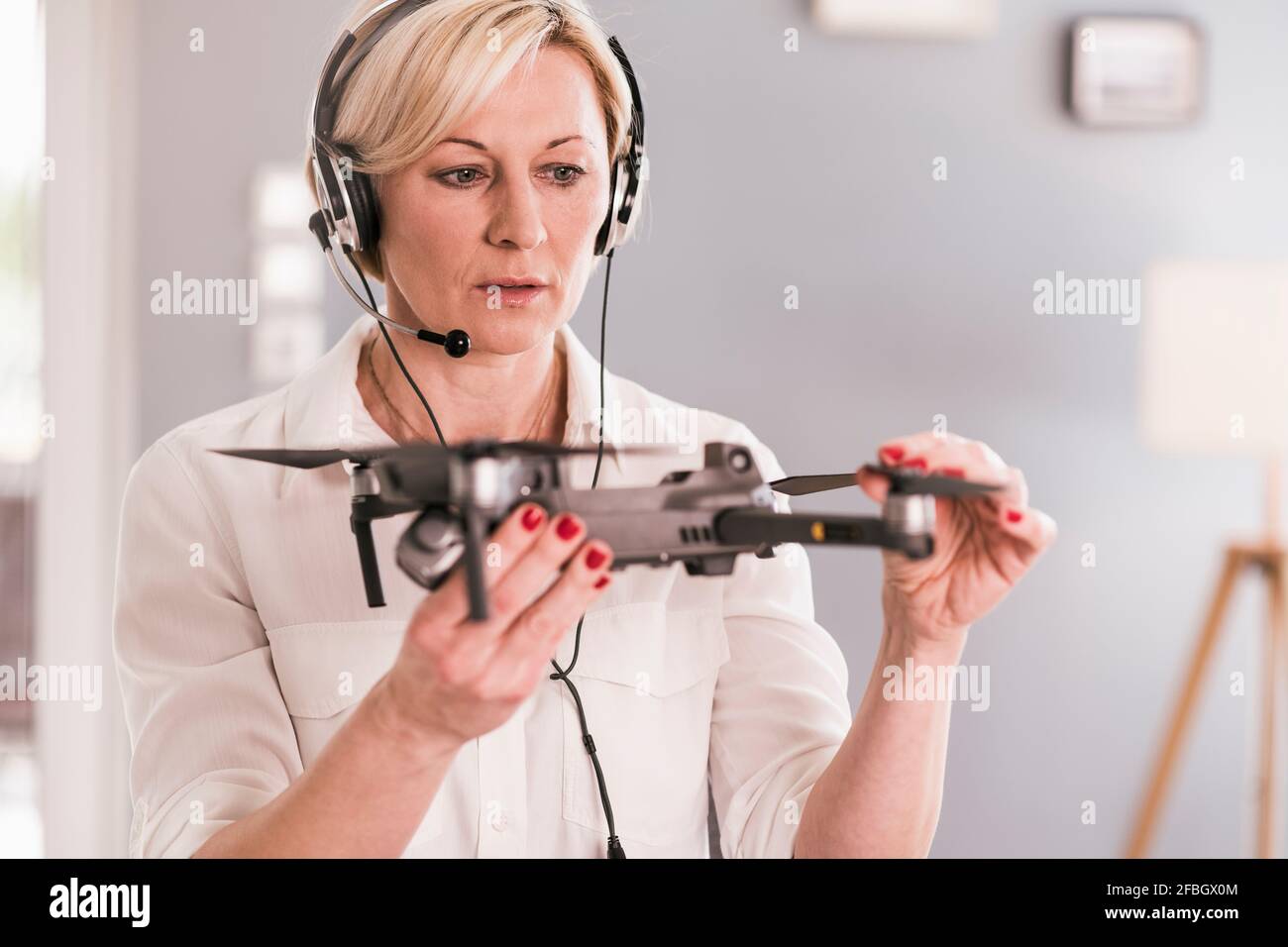 Donna imprenditore in cuffia che esamina il drone in ufficio domestico Foto Stock