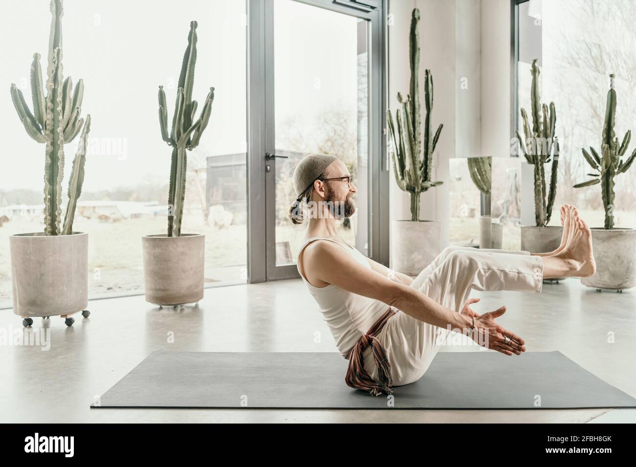 Insegnante di yoga maschile che pratica l'equilibrio del corpo su materassino da sforzo Foto Stock