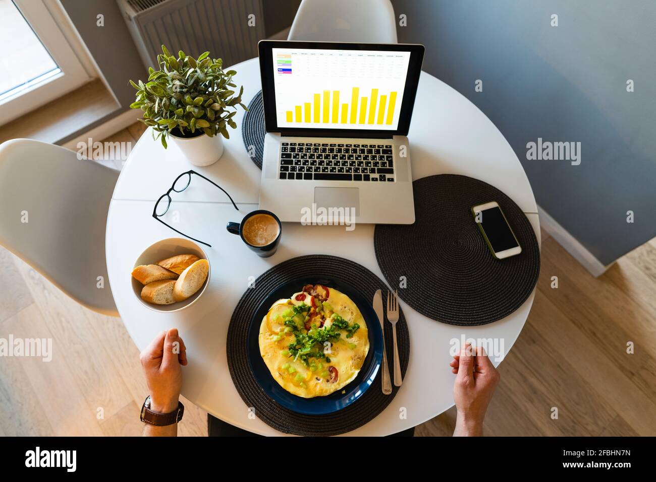 Uomo a mano sul tavolo con cibo e computer portatile a casa Foto Stock