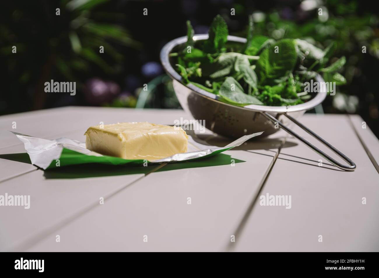 Fetta di burro da erbe miste in colander sul tavolo Foto Stock