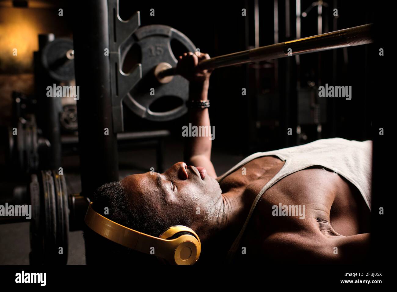 Atleta maschile che pratica la pressa da banco in palestra Foto Stock