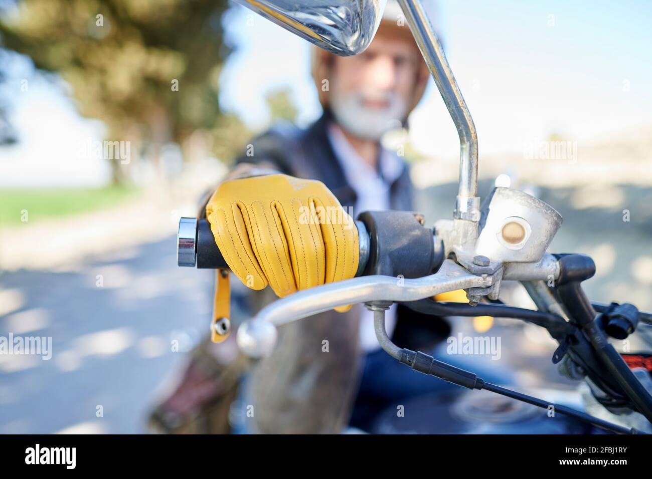 Uomo maturo con guanti gialli che tengono il manubrio mentre si è seduti  moto Foto stock - Alamy