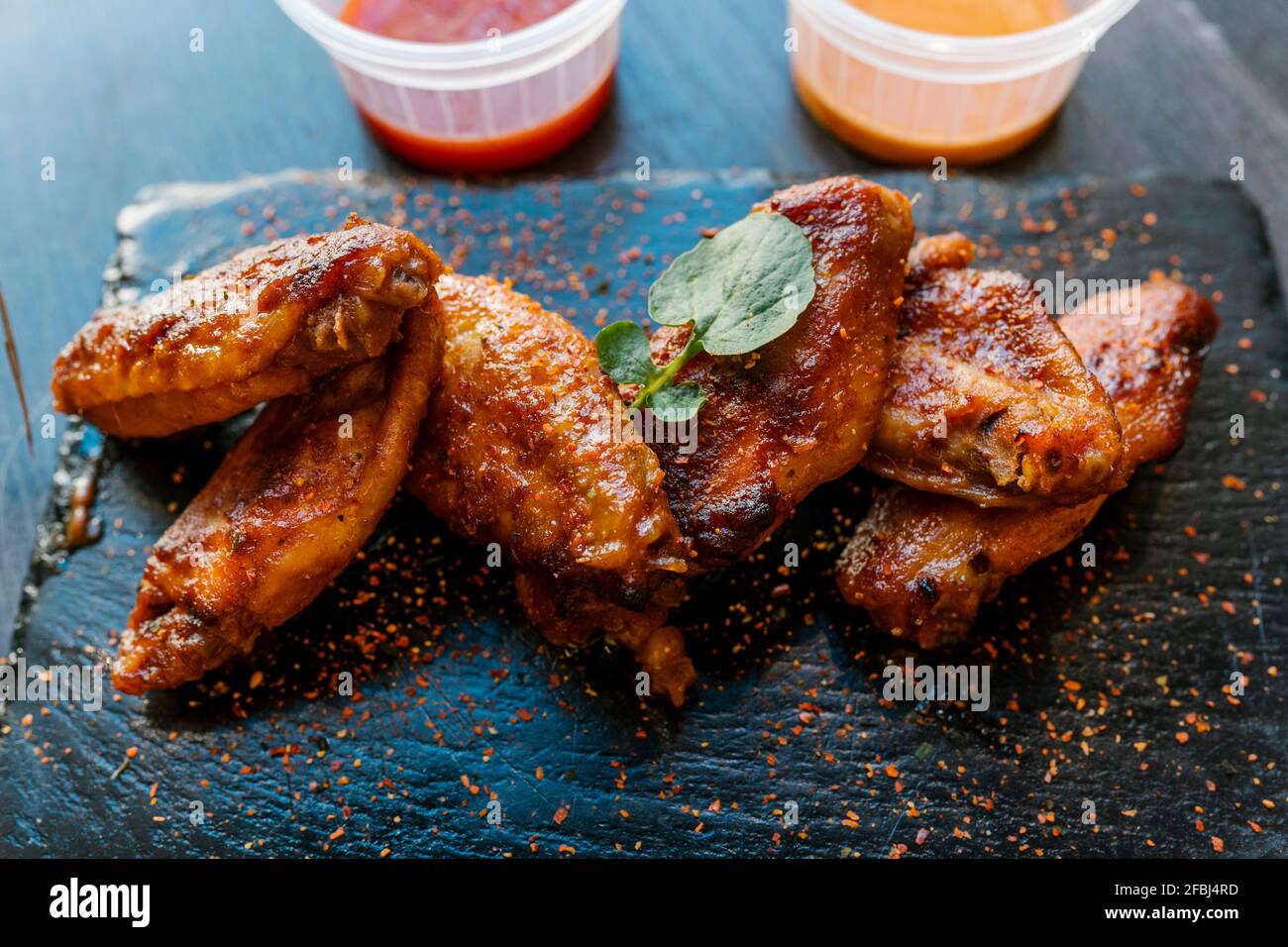 Condimento delle ali di pollo servito su piatto nero Foto Stock