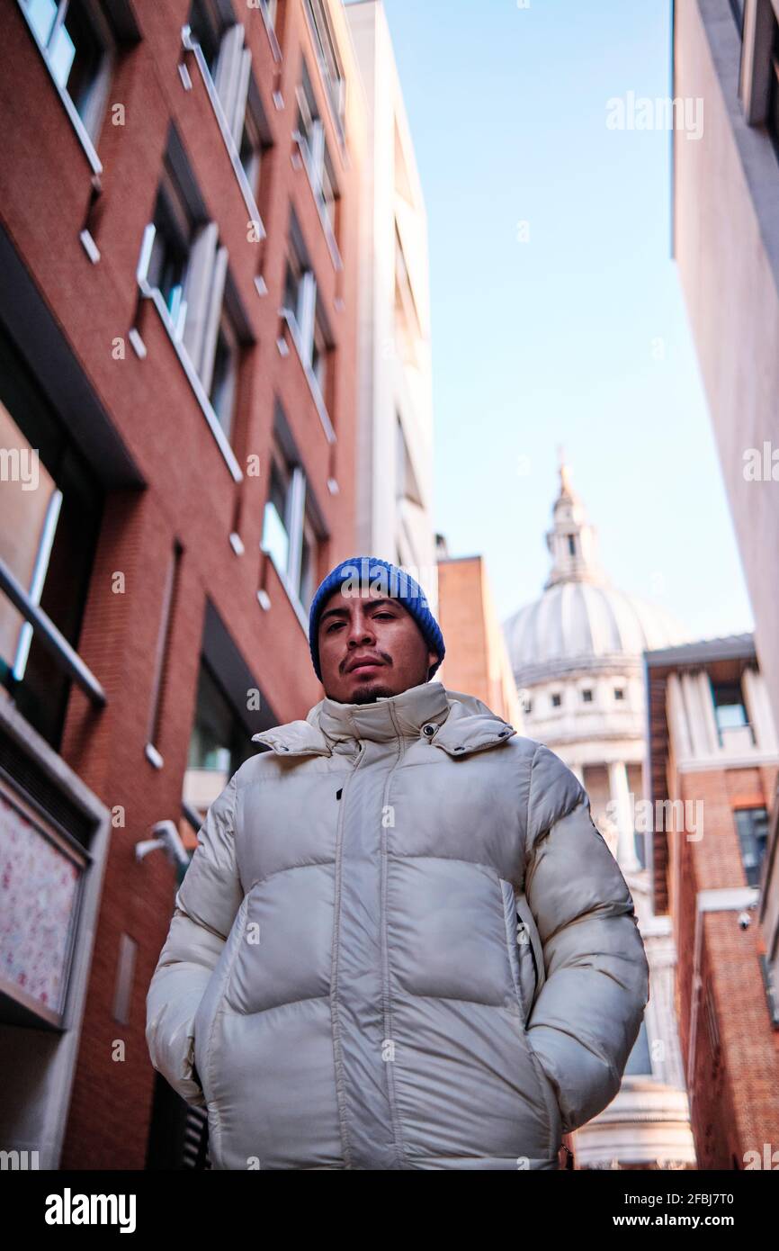 Uomo che cammina con le mani in tasche di giacca imbottita con la Cattedrale di San Paolo sullo sfondo Foto Stock