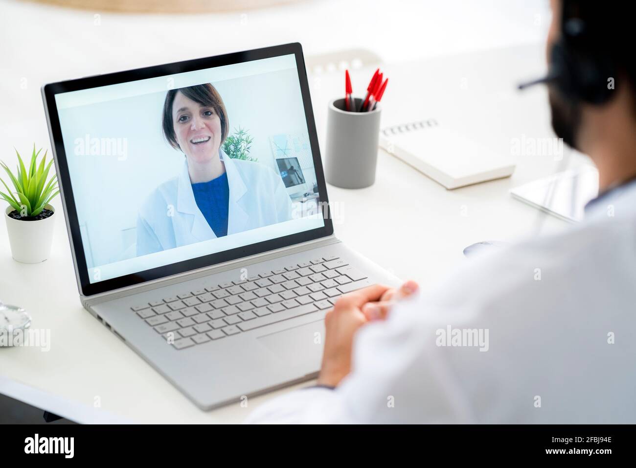 Medico maschile che discute con la collega femminile sulla videoconferenza attraverso computer portatile Foto Stock