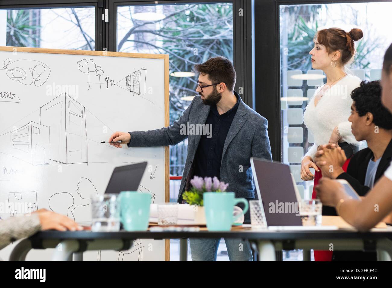 Giovane imprenditore che dà la presentazione ai colleghi in riunione Foto Stock