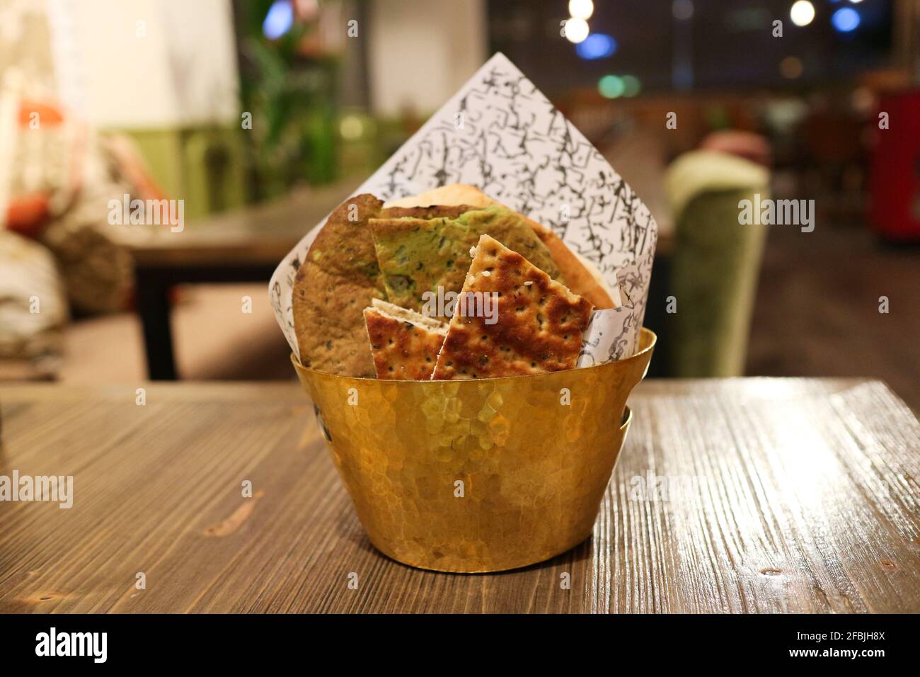 Kuwait City - Kuwait: 10 aprile 2021: Ciotola di ottone con cracker su rustico piano in legno Foto Stock