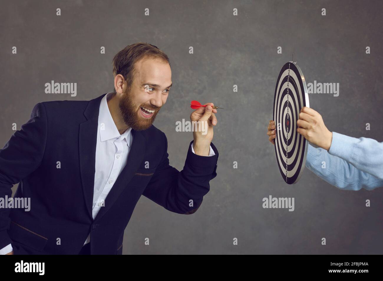 Uomo d'affari che mira a dart a dartboard come metafora per impostare gli obiettivi e obiettivi Foto Stock