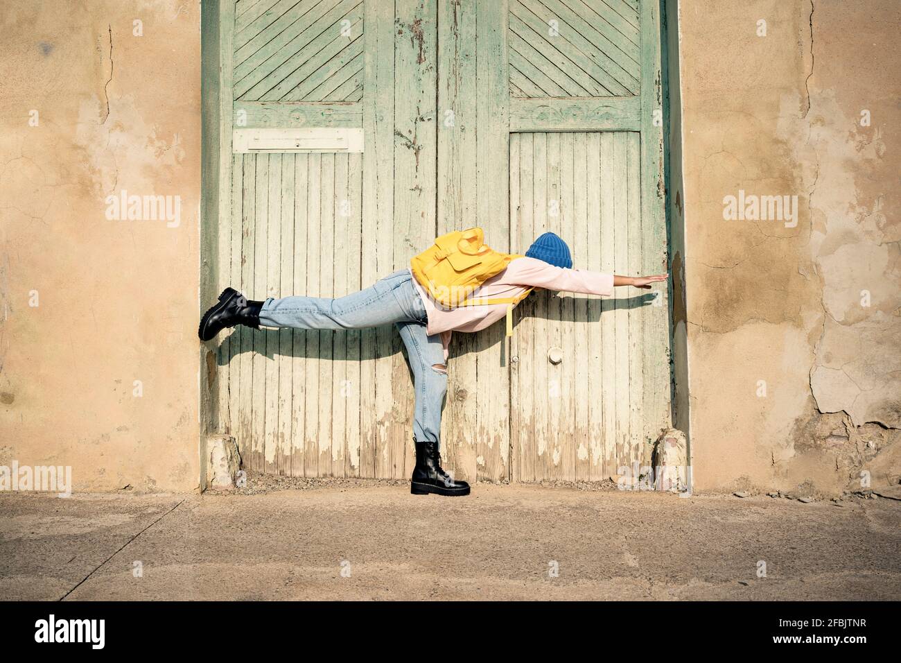 Donna con zaino che allunga la mano mentre si trova su una gamba durante il giorno di sole Foto Stock