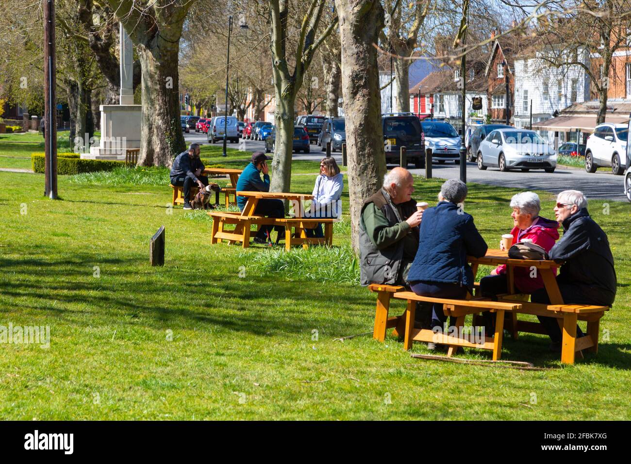 Persone sedute all'esterno su panchine poste lungo la strada alta, tenterden, kent, uk Foto Stock