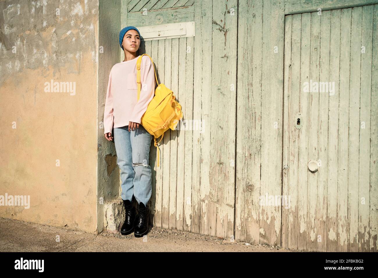 Donna che contempla mentre si trova in piedi con lo zaino davanti al legno porta Foto Stock
