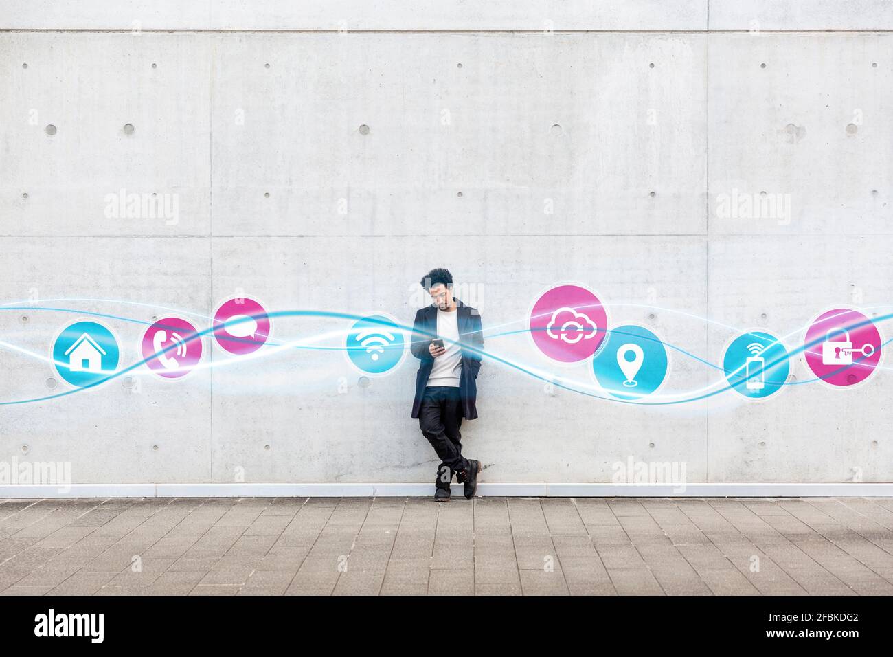 Giovane uomo che usa il telefono cellulare mentre si è in piedi con le icone andamento delle onde incandescenti sul sentiero Foto Stock