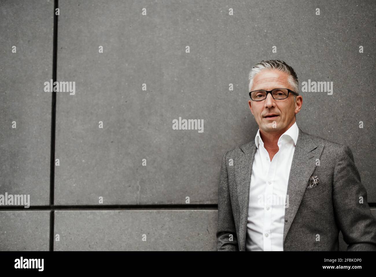 Imprenditore maschile in blazer grigio giacca contro muro Foto Stock