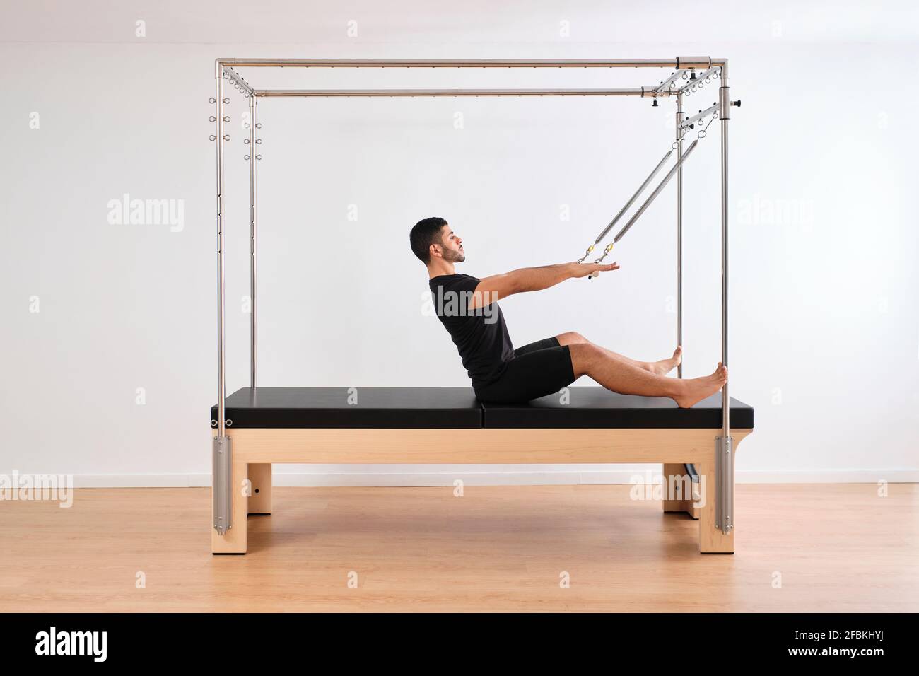 Uomo medio adulto seduto su pilates macchina in palestra Foto Stock