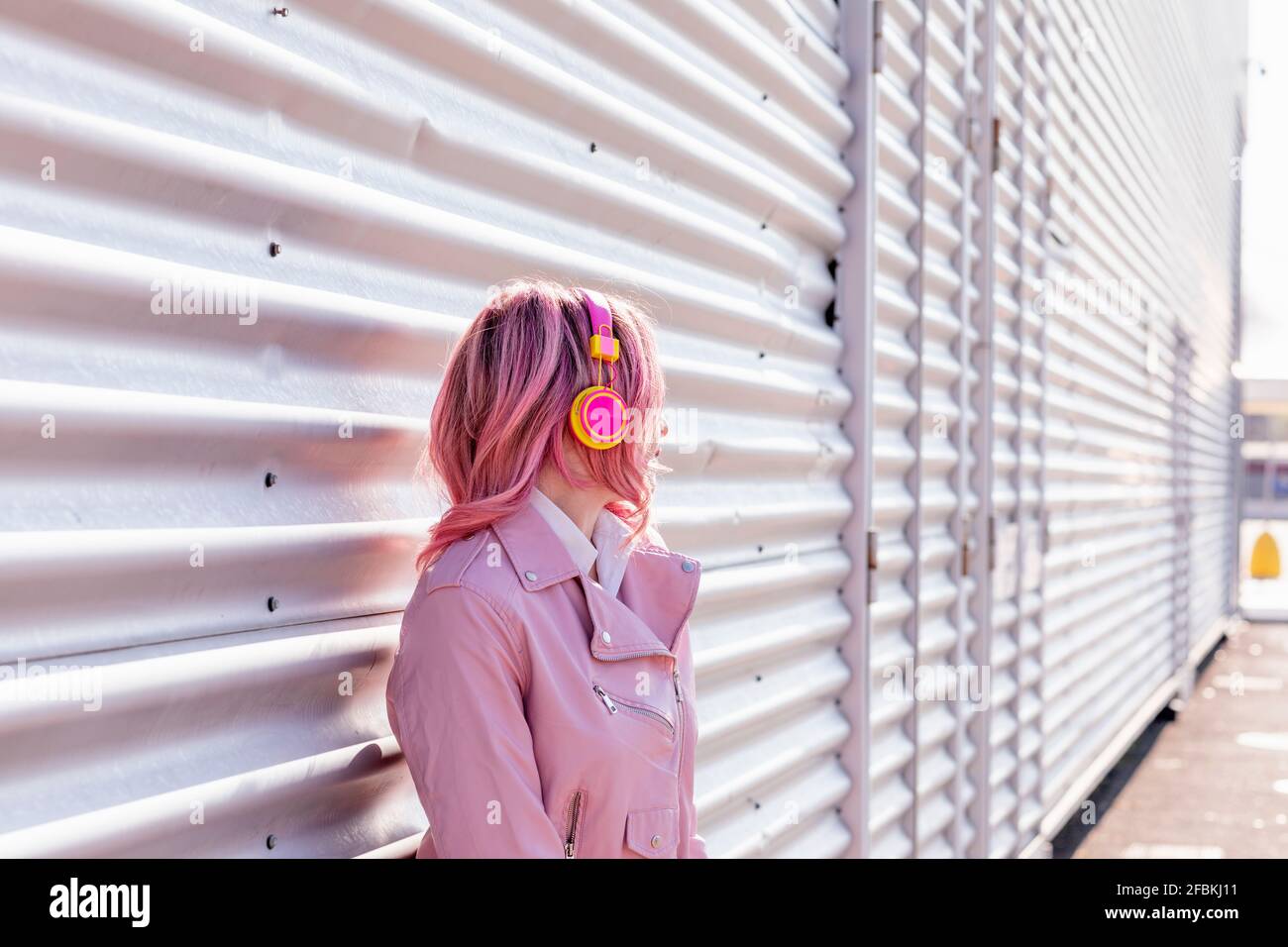 Donna con capelli rosa in piedi davanti alla parete di metallo Foto Stock