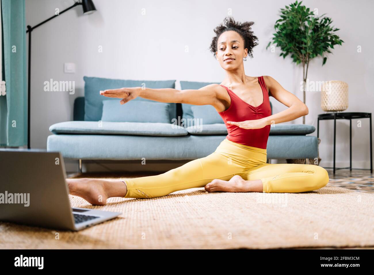 Donna che fa yoga mentre si guarda tutorial online su computer portatile a. casa Foto Stock