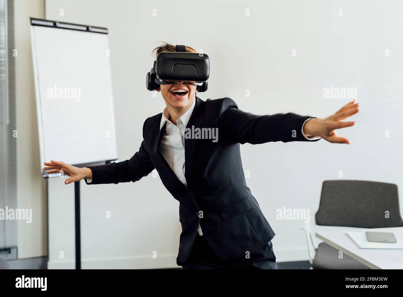 Allegra professionista di affari femminile con simulatore di realtà virtuale in ufficio Foto Stock