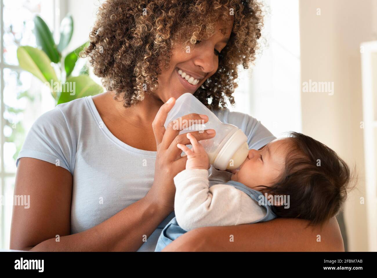 Buon biberon madre che alimenta la sua bambina a casa Foto Stock